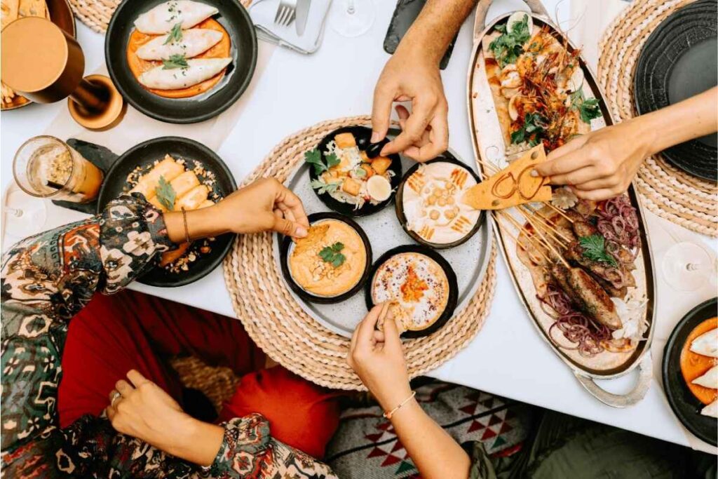 Fotografia przedstawia wspólny posiłek, który polega na dzieleniu się jedzeniem