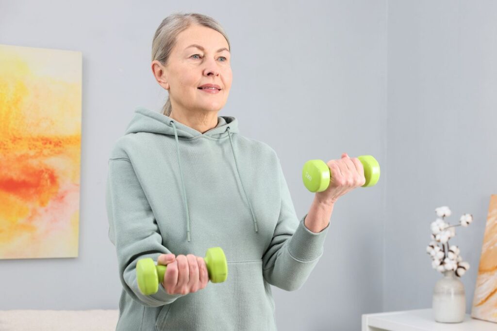 Kobieta trenuje z hantlami, żeby zbudować masę mięśniową i przyspieszyć metabolizm