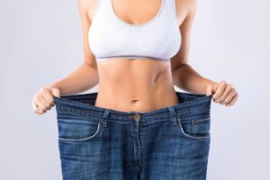 Kobieta przymierza spodnie, które są już za duże, bo przyspieszyła metabolizm