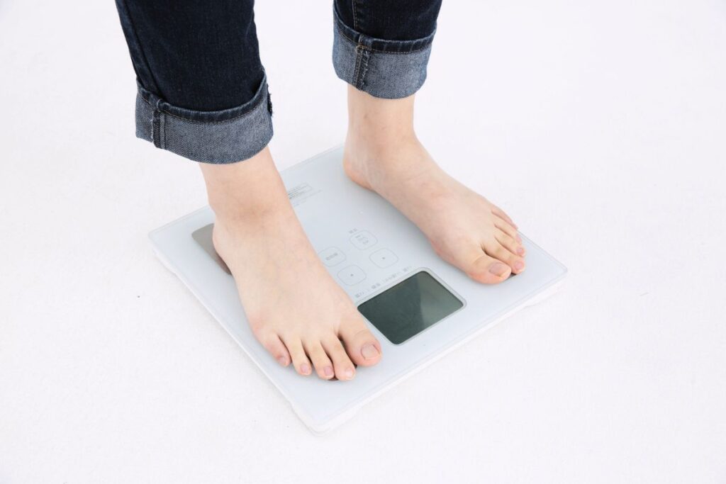 Kobieta wchodzi na wagę, żeby ocenić proces odchudzania